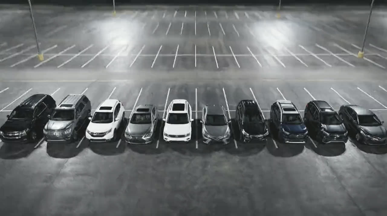 Ten of the fleet seen from above at an angle, parked side by side under lot lights.